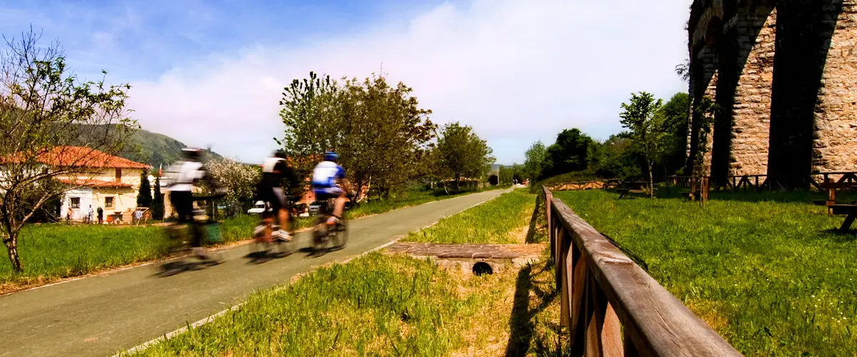 Ciclistas en una via verde junto a un acueducto